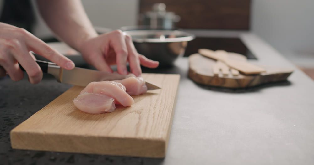 ผู้ชายกำลังหั่นไก่ขวางลายเส้นช่วยให้ไก่นุ่ม
